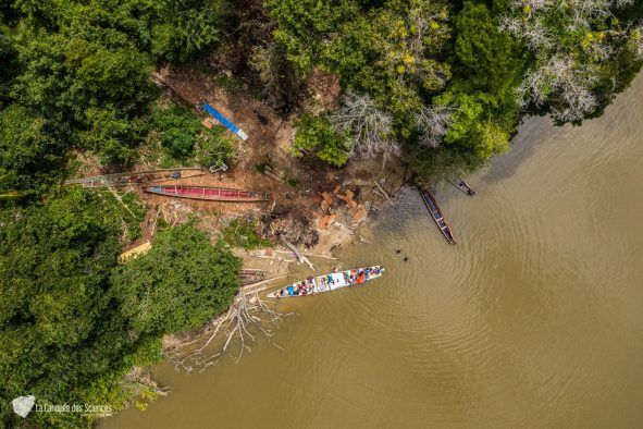 Une vue aérienne d'une rivière entourée d'arbres et d'un bateau.