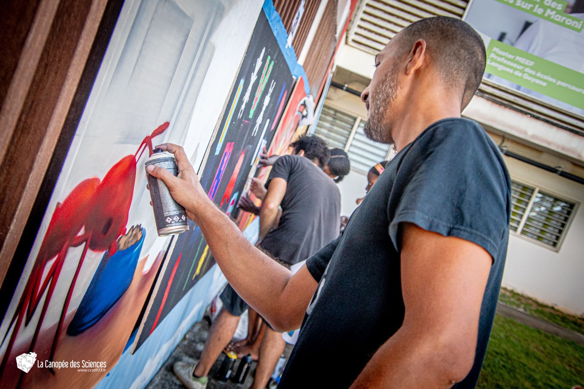 Un homme peint à la bombe une fresque murale sur un mur.