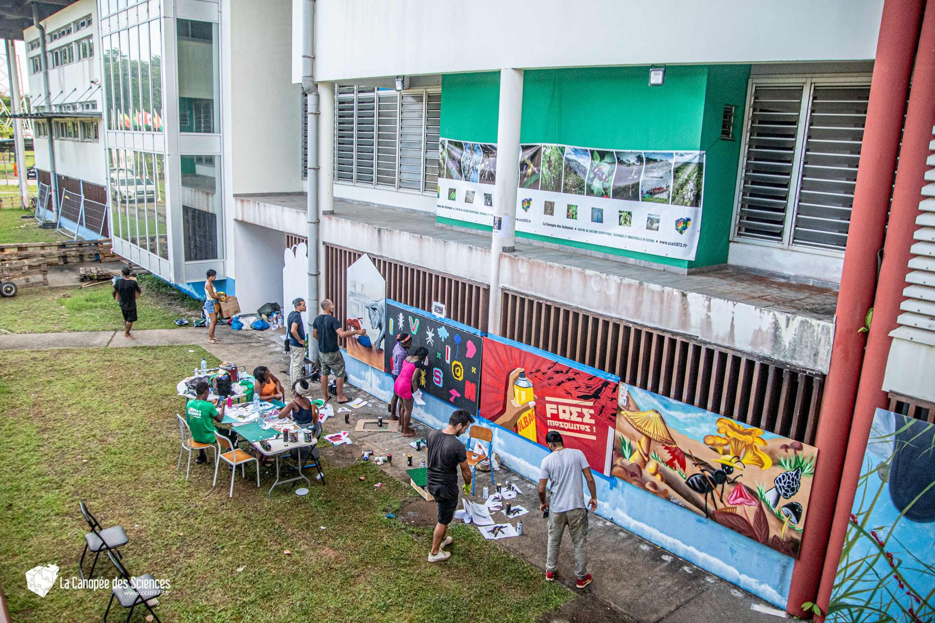 Un groupe de personnes peint une fresque sur le côté d'un bâtiment.