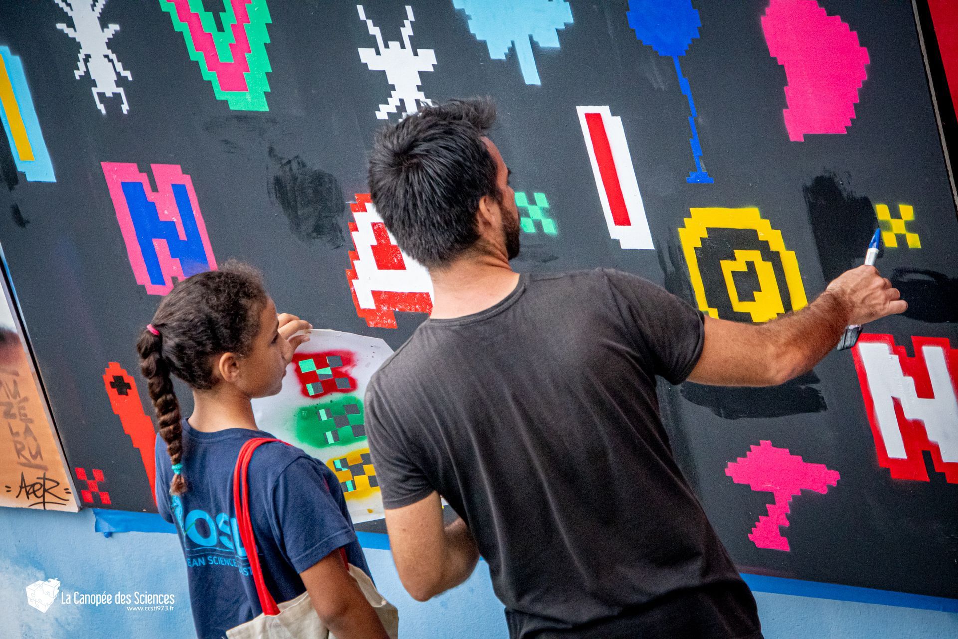 Un homme et une fille regardent un tableau sur un mur.