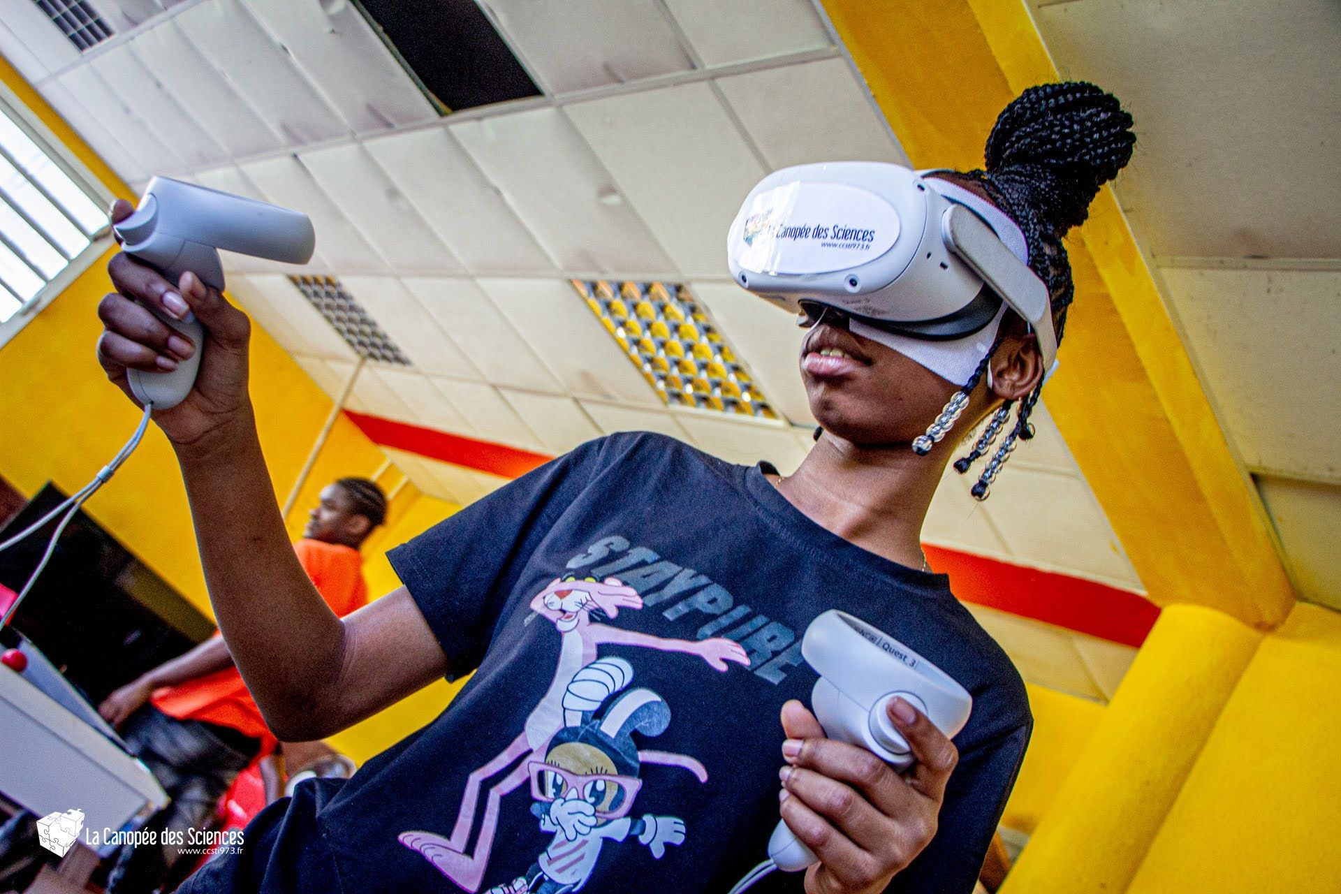 Une femme porte un casque de réalité virtuelle et tient une manette.