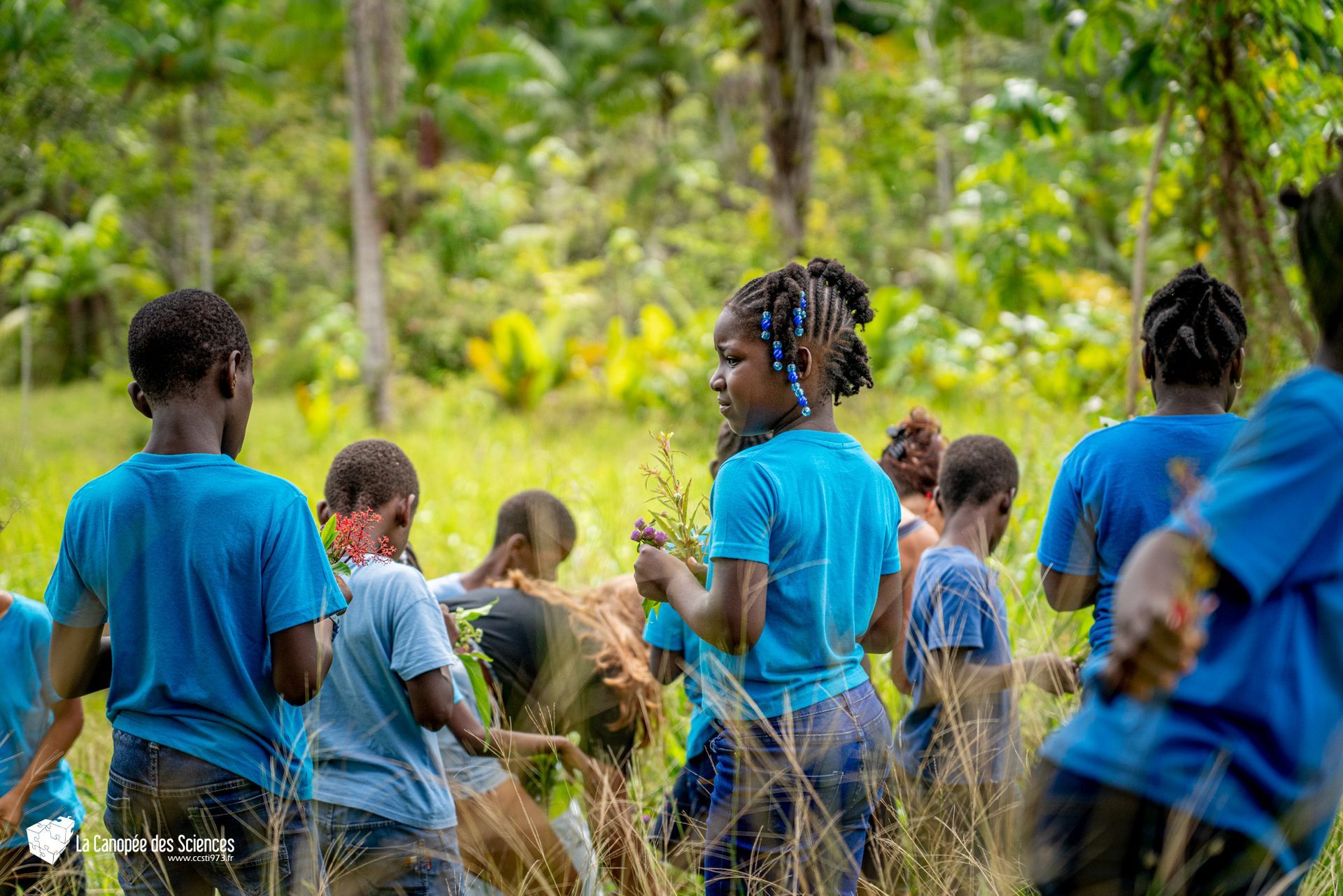 Un groupe d'enfants en chemises bleues se tiennent dans un champ.