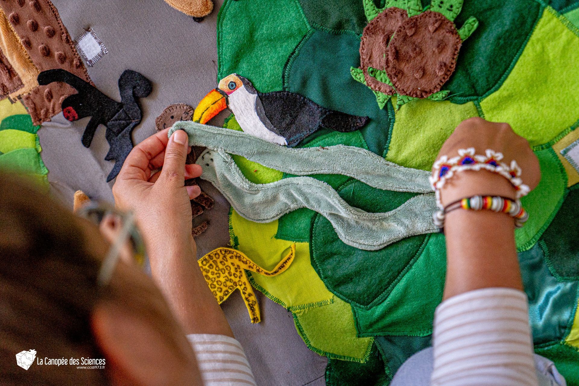 Une personne joue avec une couverture sur laquelle sont posés des animaux en peluche.