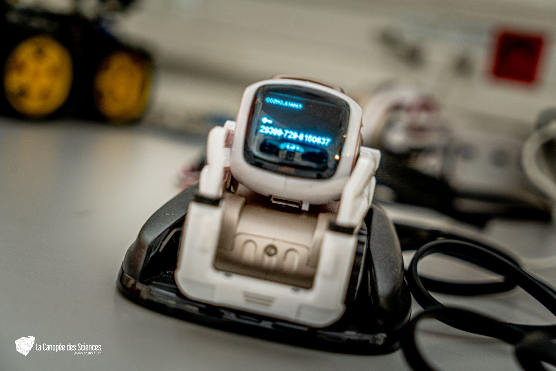 Un petit robot est assis sur un chargeur sur une table.