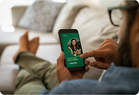 Homem usando um telefone com uma interface verde enquanto relaxa no sofá.