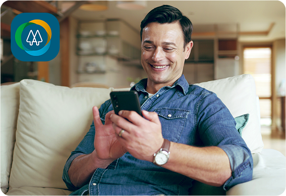 Homem sorridente em um sofá, olhando para um celular. O ícone do aplicativo está visível.