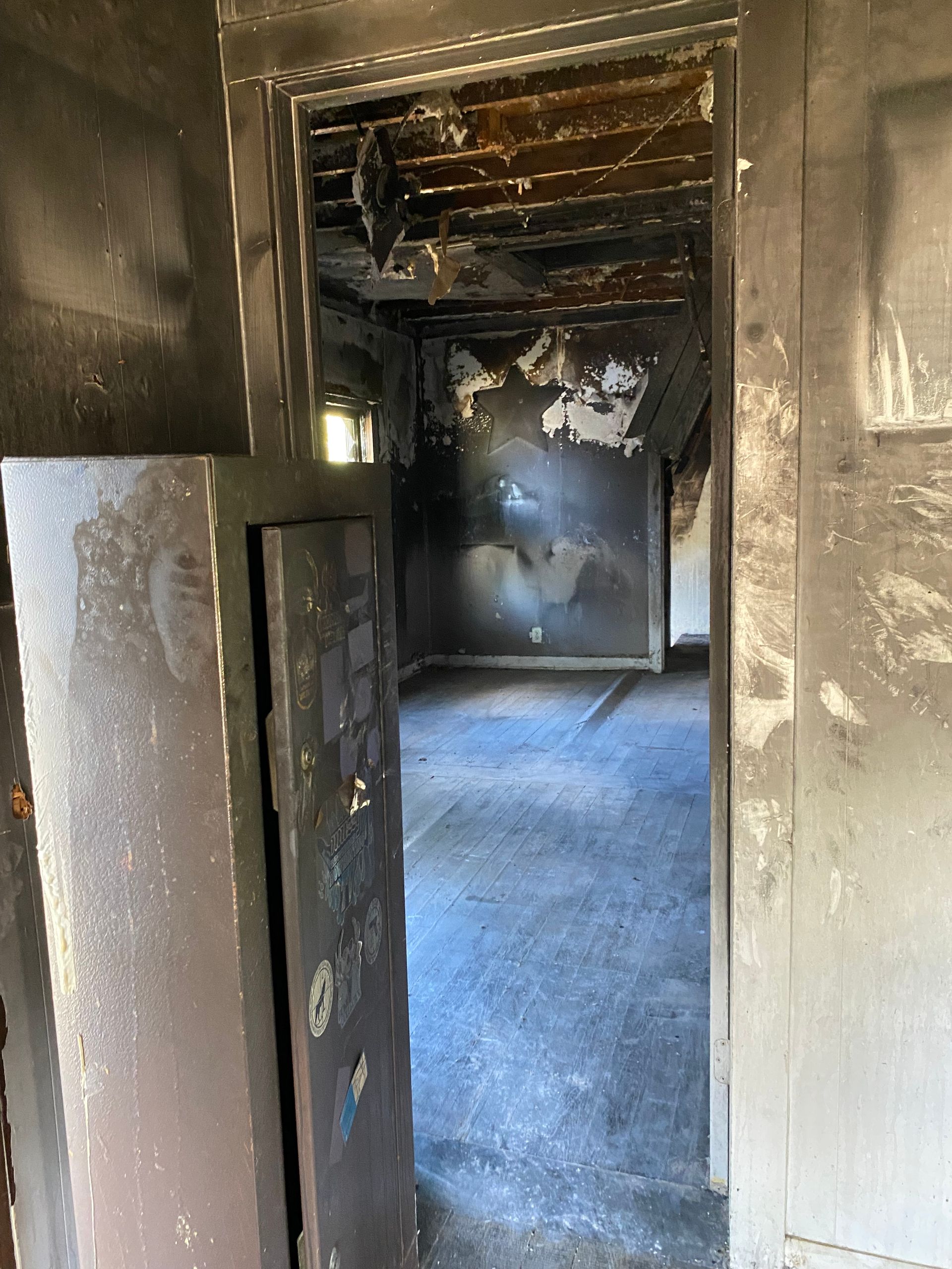 Charred doorway leading into a fire-damaged room with soot-stained walls and exposed ceiling beams