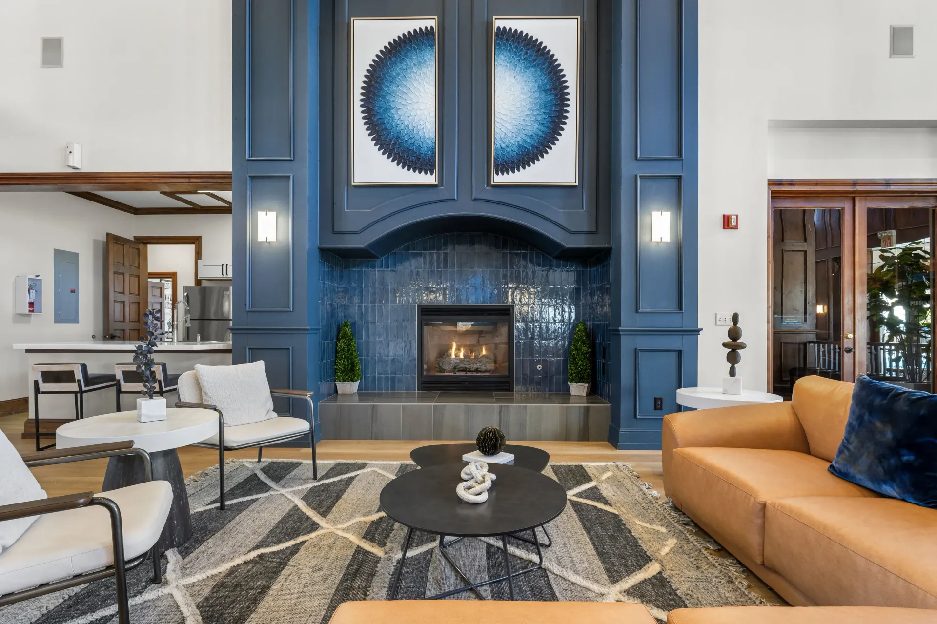 Elegant community lounge with a tall blue fireplace, modern seating, and geometric rug.