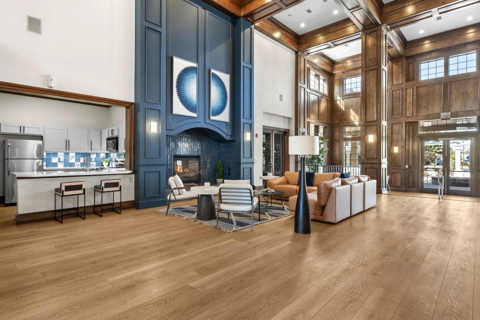 Open, high-ceiling community lobby with a blue fireplace surround, wood paneling, and seating.