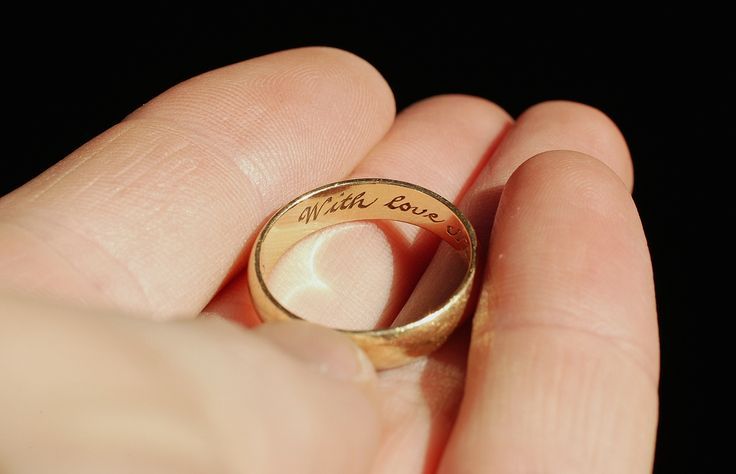 Una persona tiene in mano un anello d'oro con la scritta