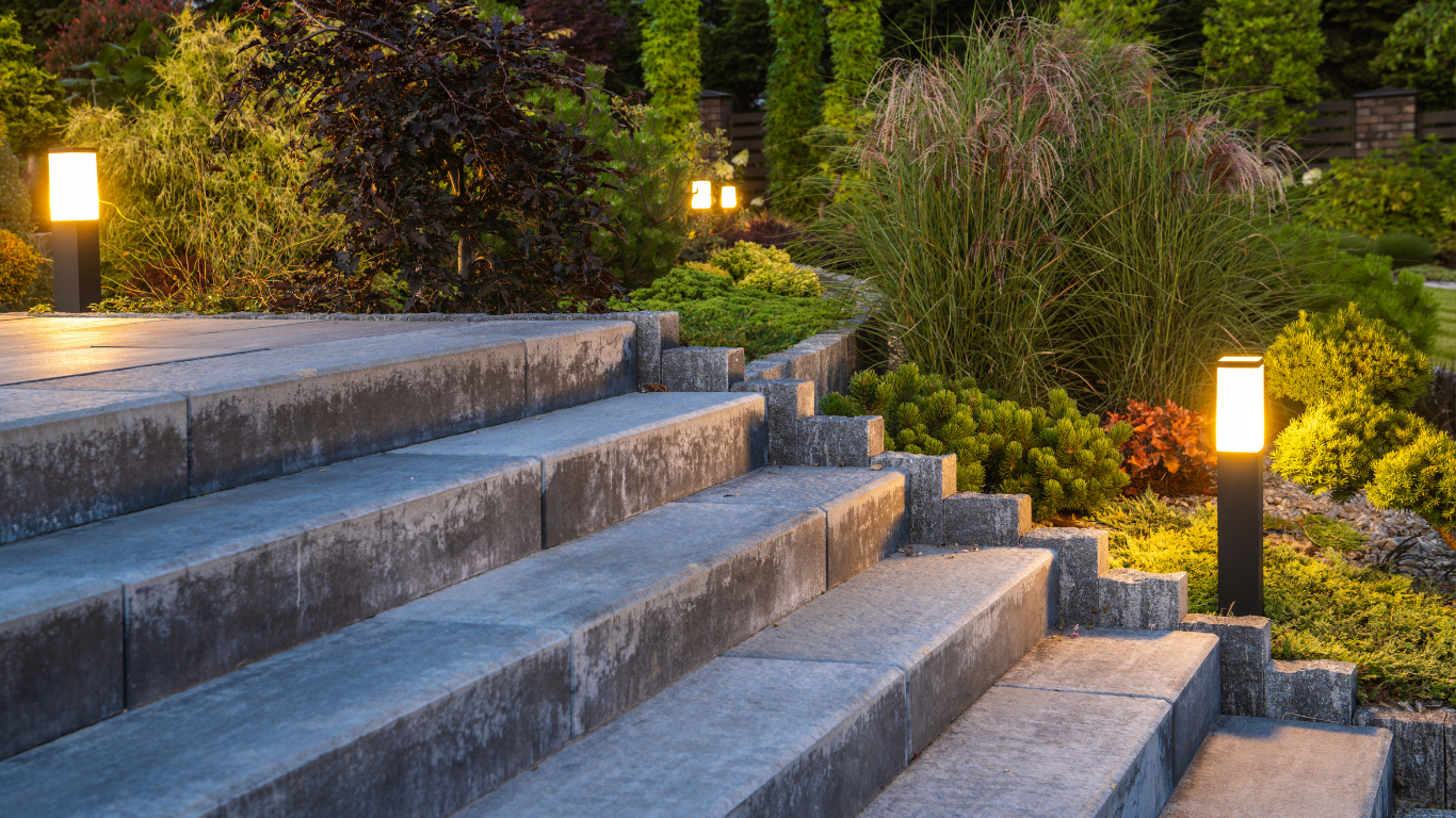 Stone steps in a landscaped garden at dusk, lit by warm pathway lights among greenery