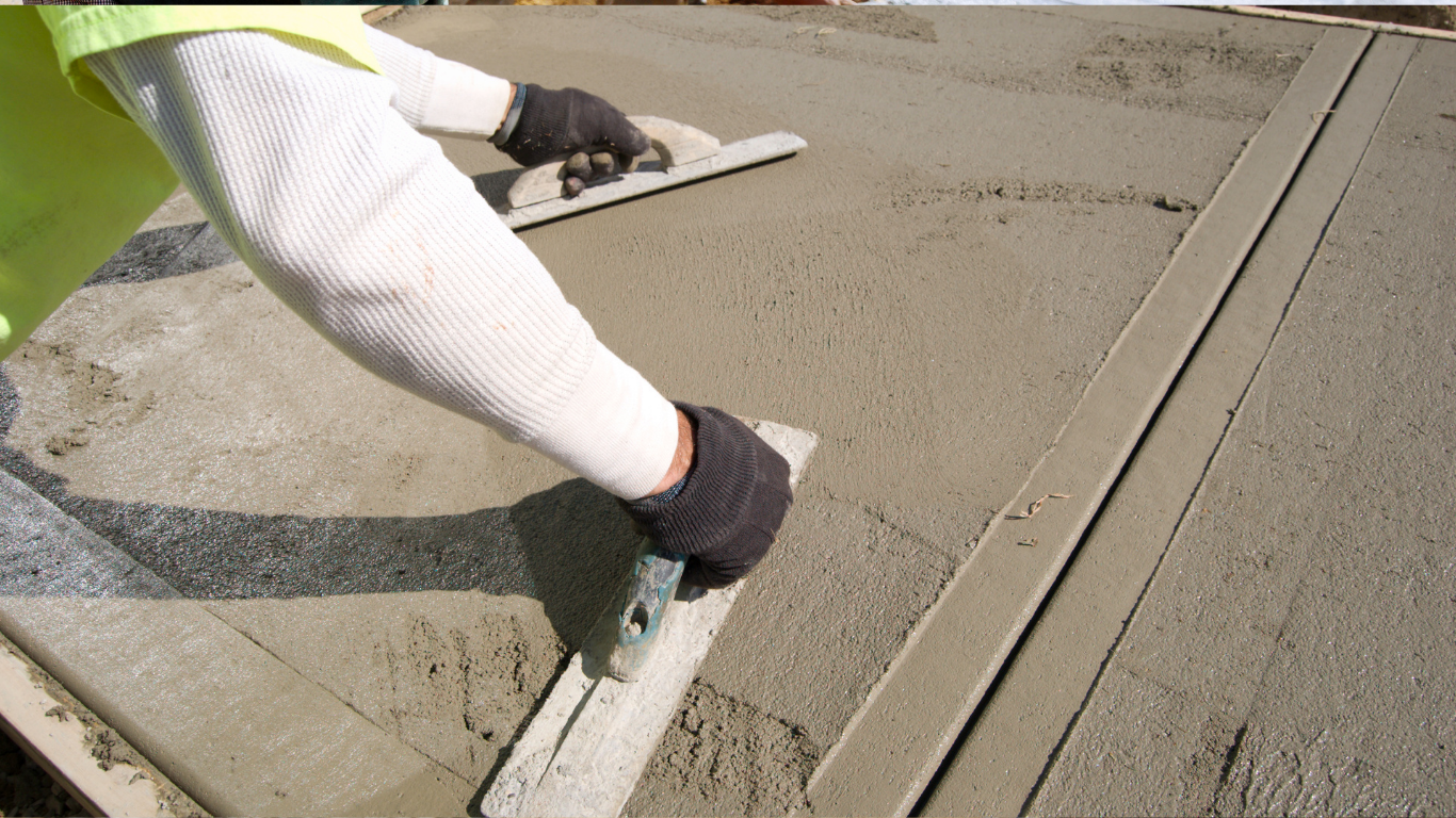 Construction worker smoothing wet concrete with a trowel on a sidewalk edge