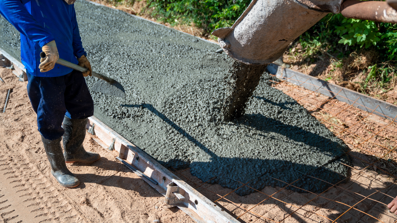 Worker pouring wet concrete into a foundation form outdoors
