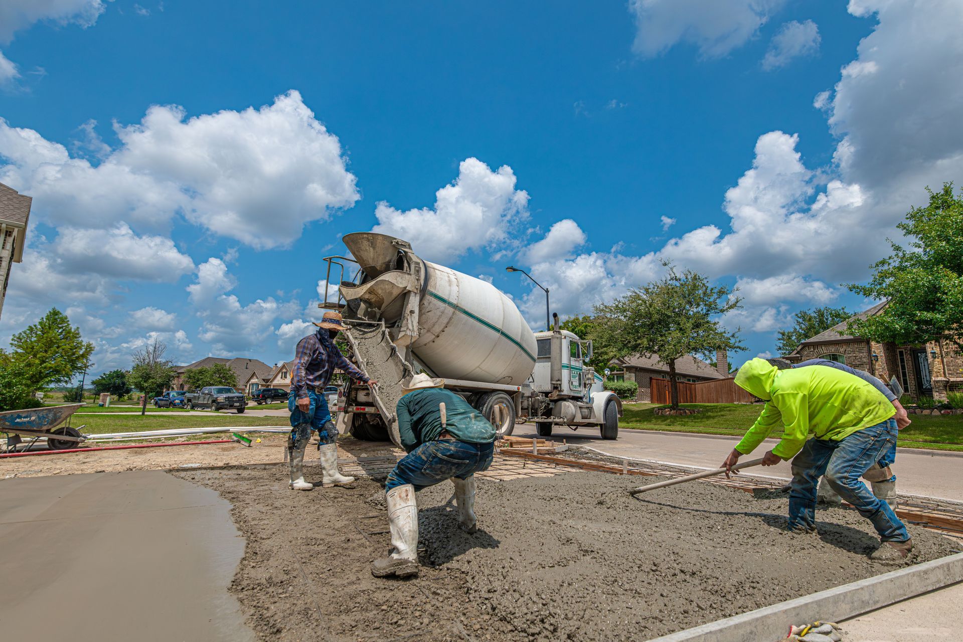 Construction workers pouring concrete on a road under a bright blue sky
