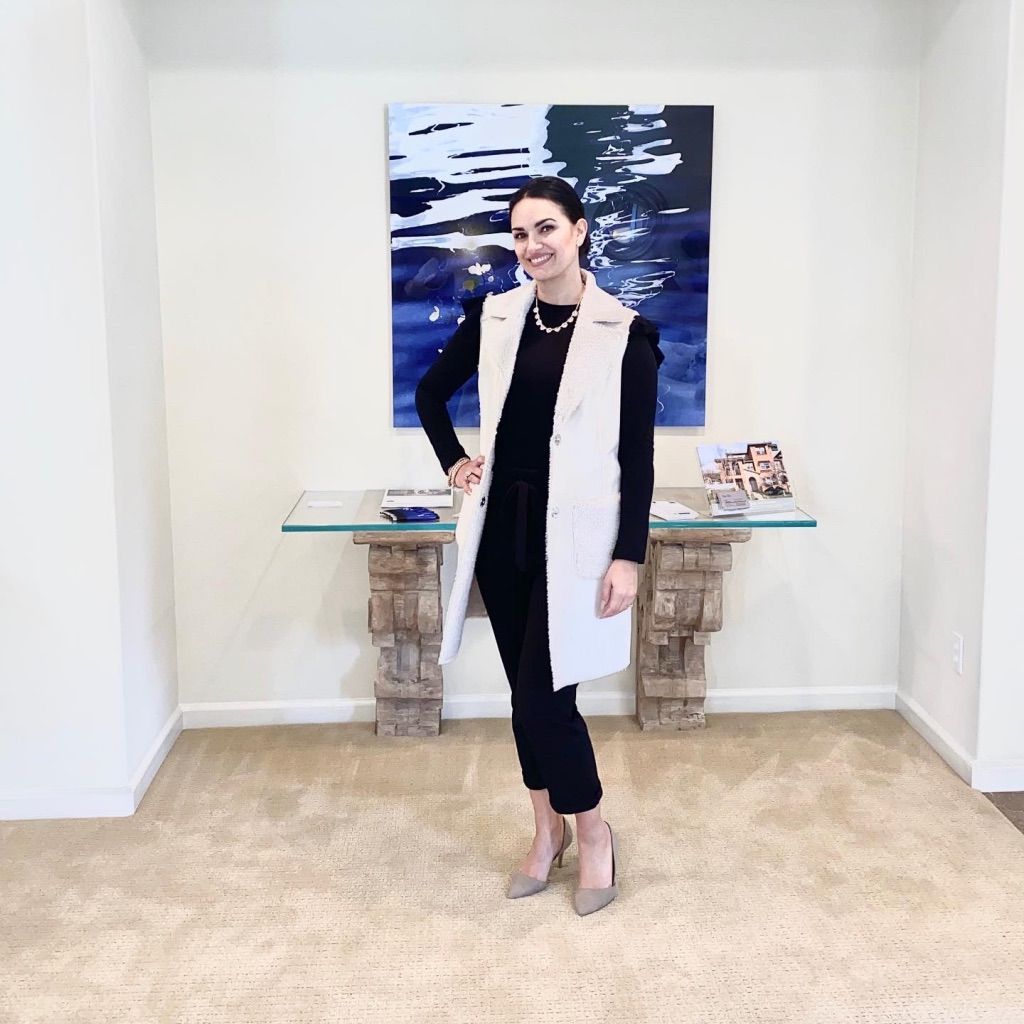 Woman standing in a hallway beside a glass table with blue abstract wall art behind her