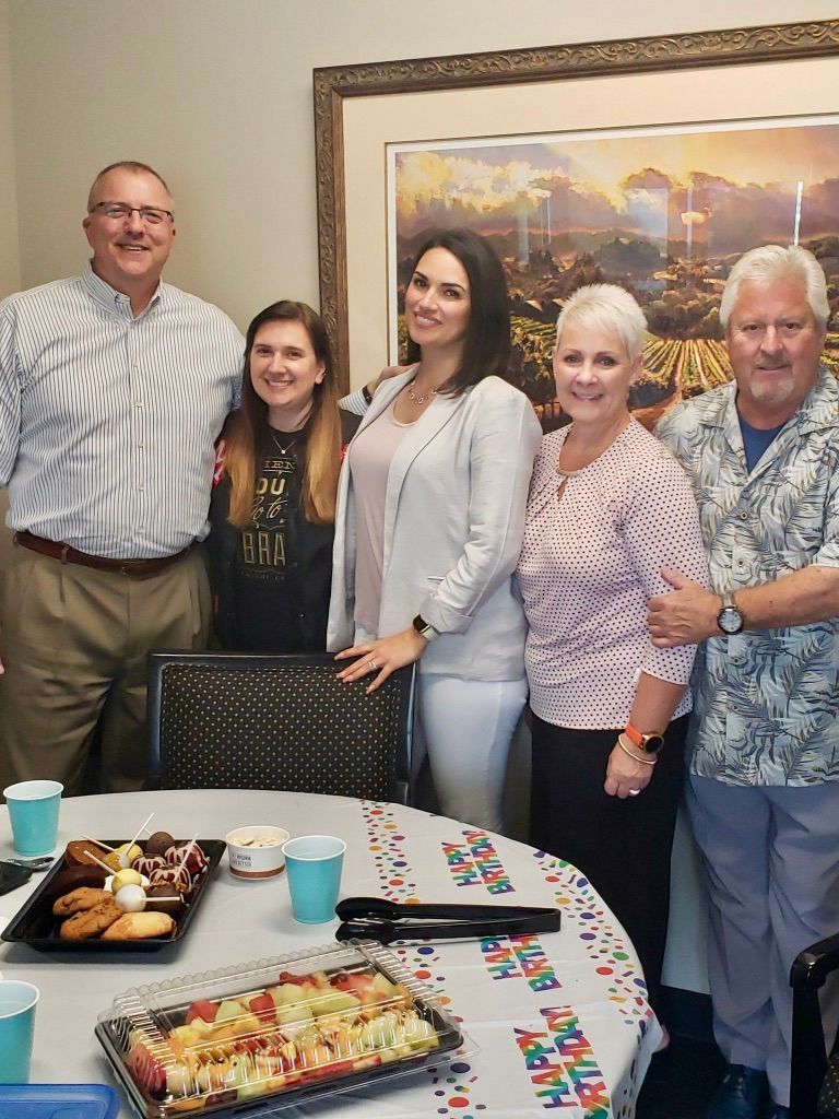 Five people smiling behind a table with snacks and blue cups at a party or family gathering
