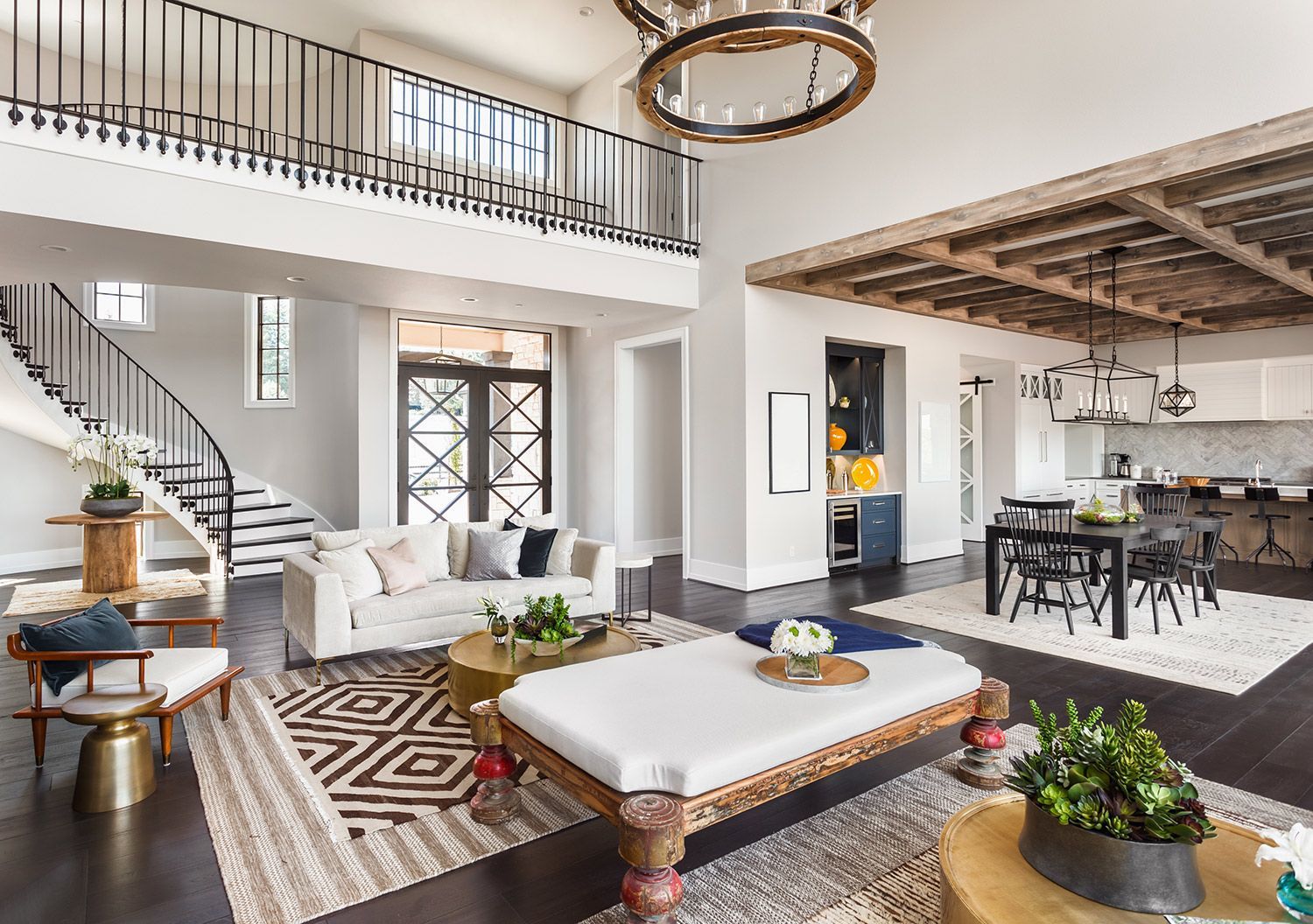 Bright airy living room with white sofa, staircase, loft balcony, and adjoining dining area