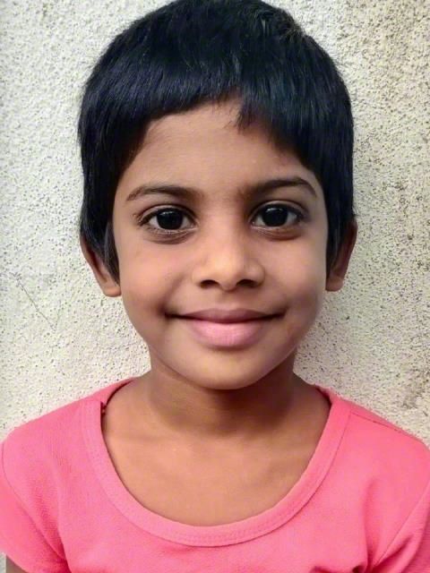 Smiling child in a pink shirt against a light wall