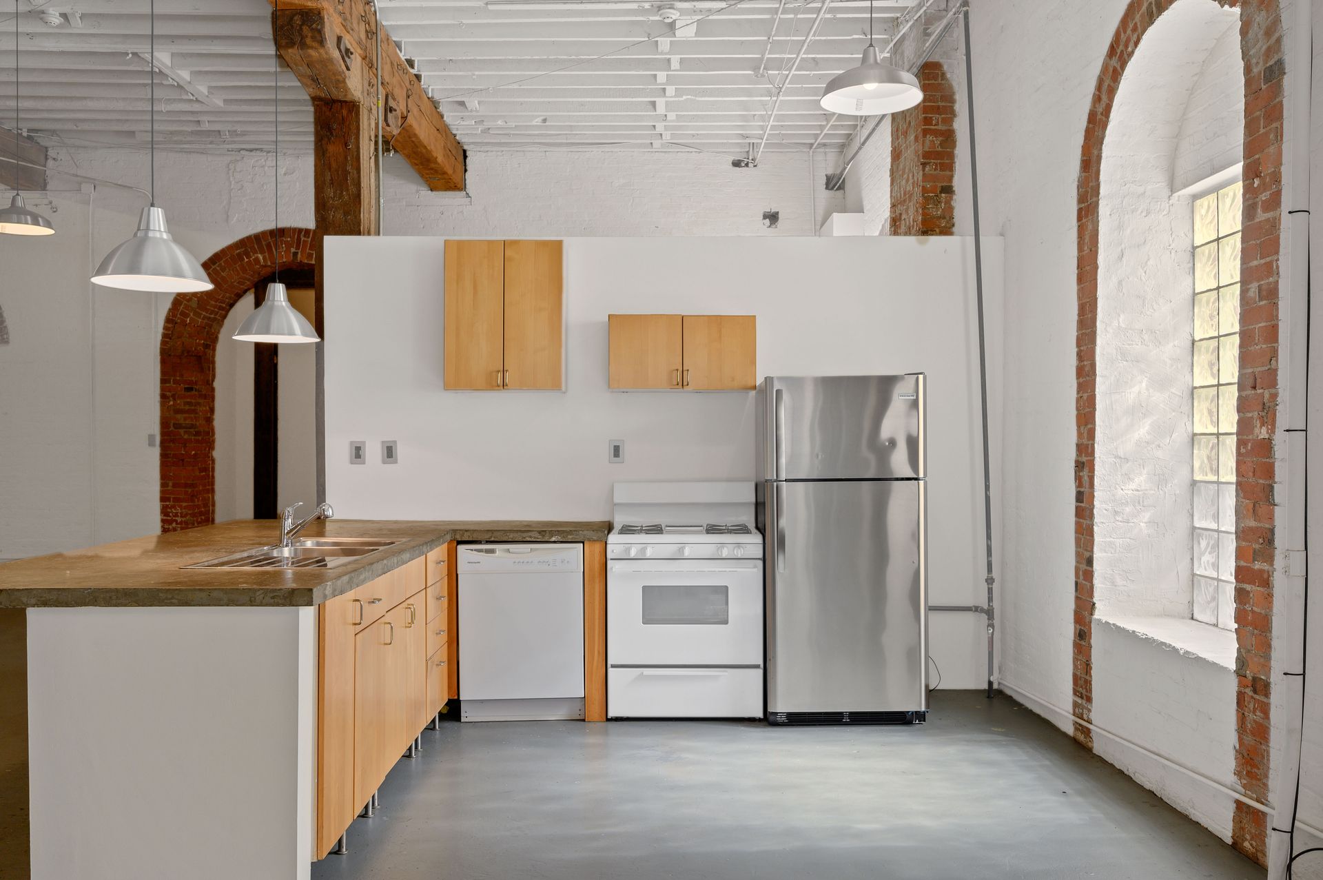 An empty kitchen with stainless steel appliances and wooden cabinets