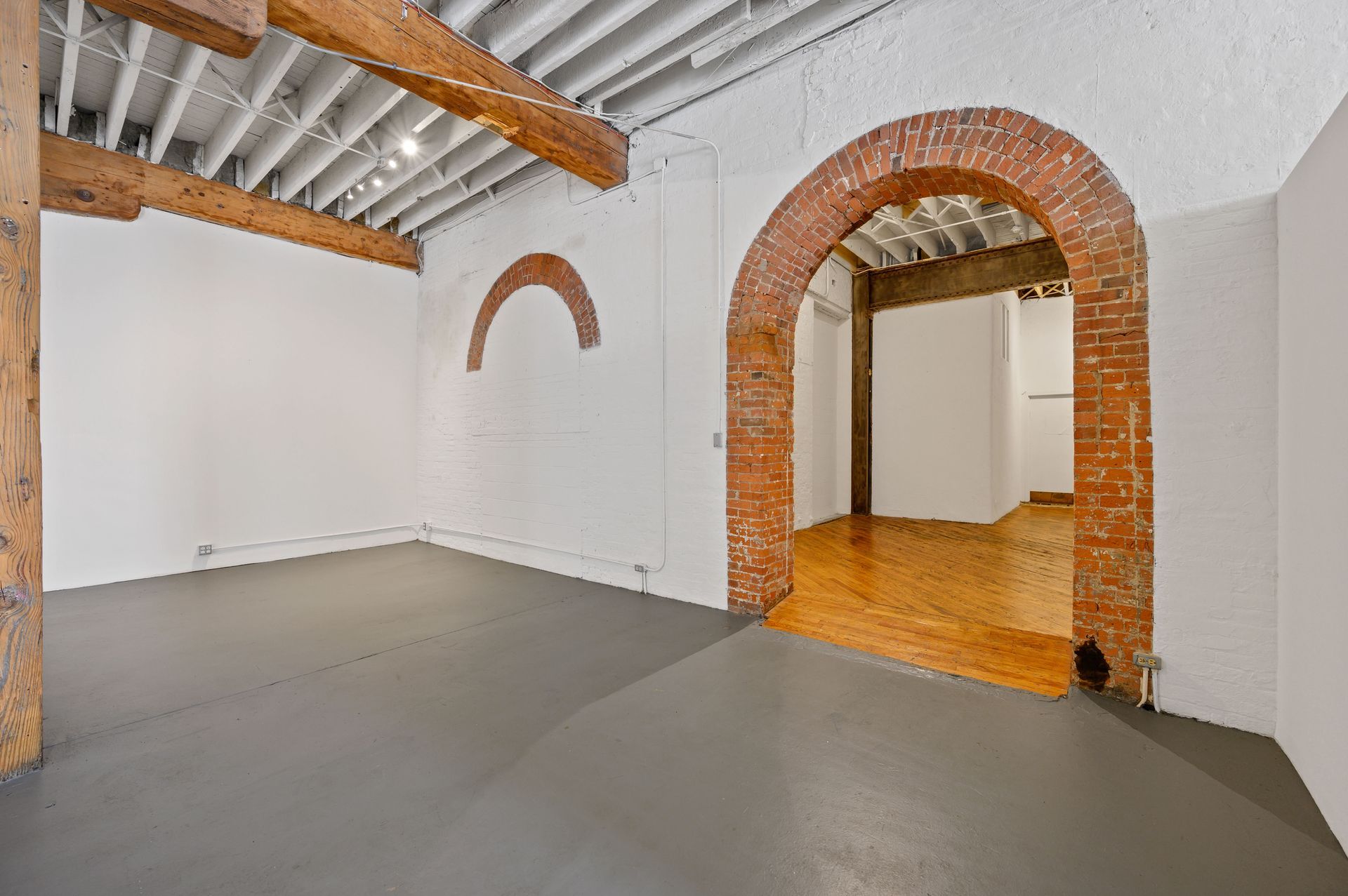 An empty room with a brick archway and a wooden floor.