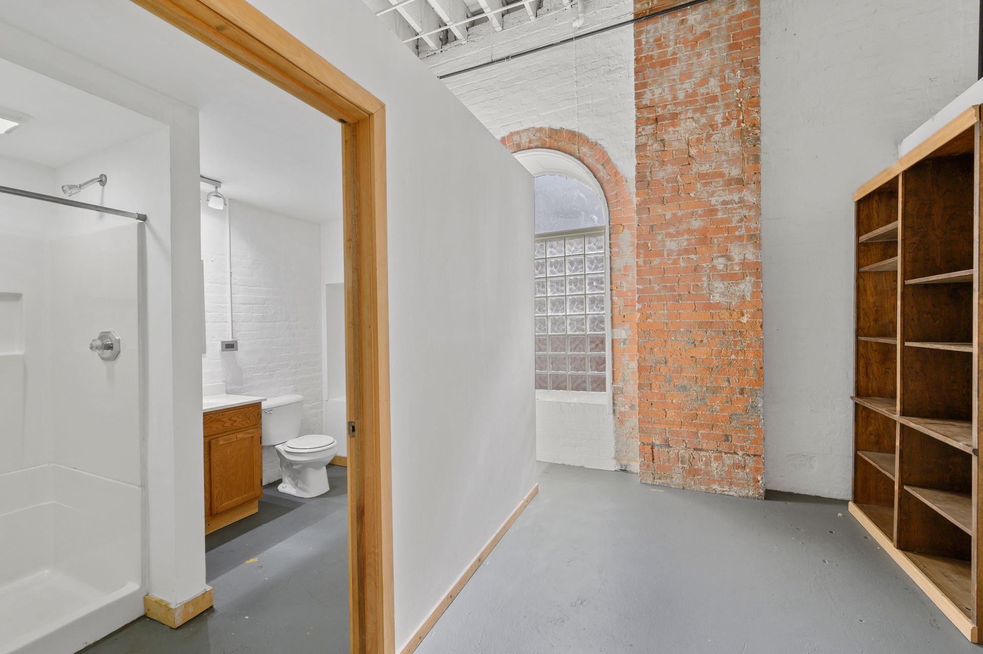 A bathroom with a toilet , sink , shower and brick wall.