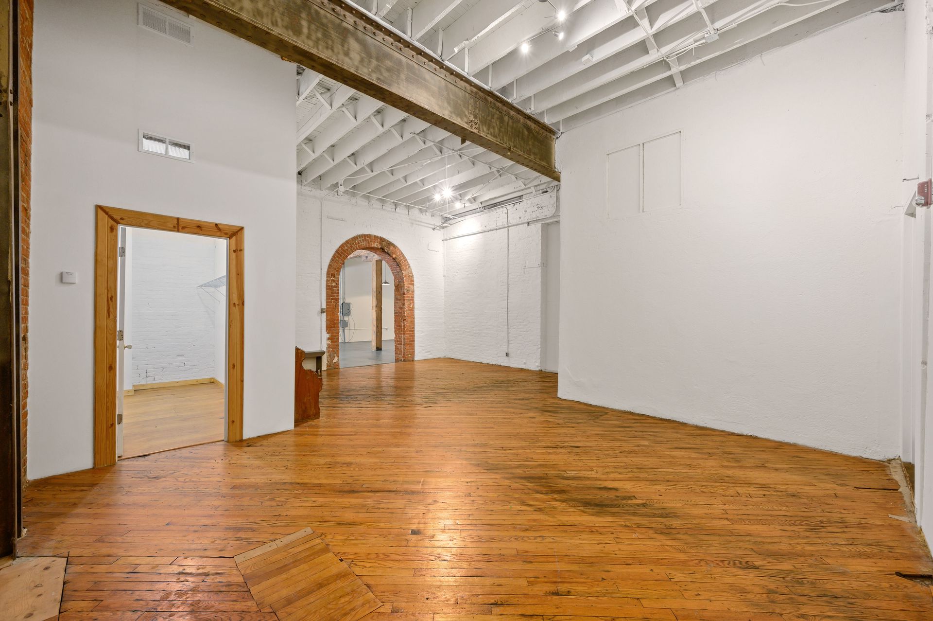 A large empty room with wooden floors and white walls.
