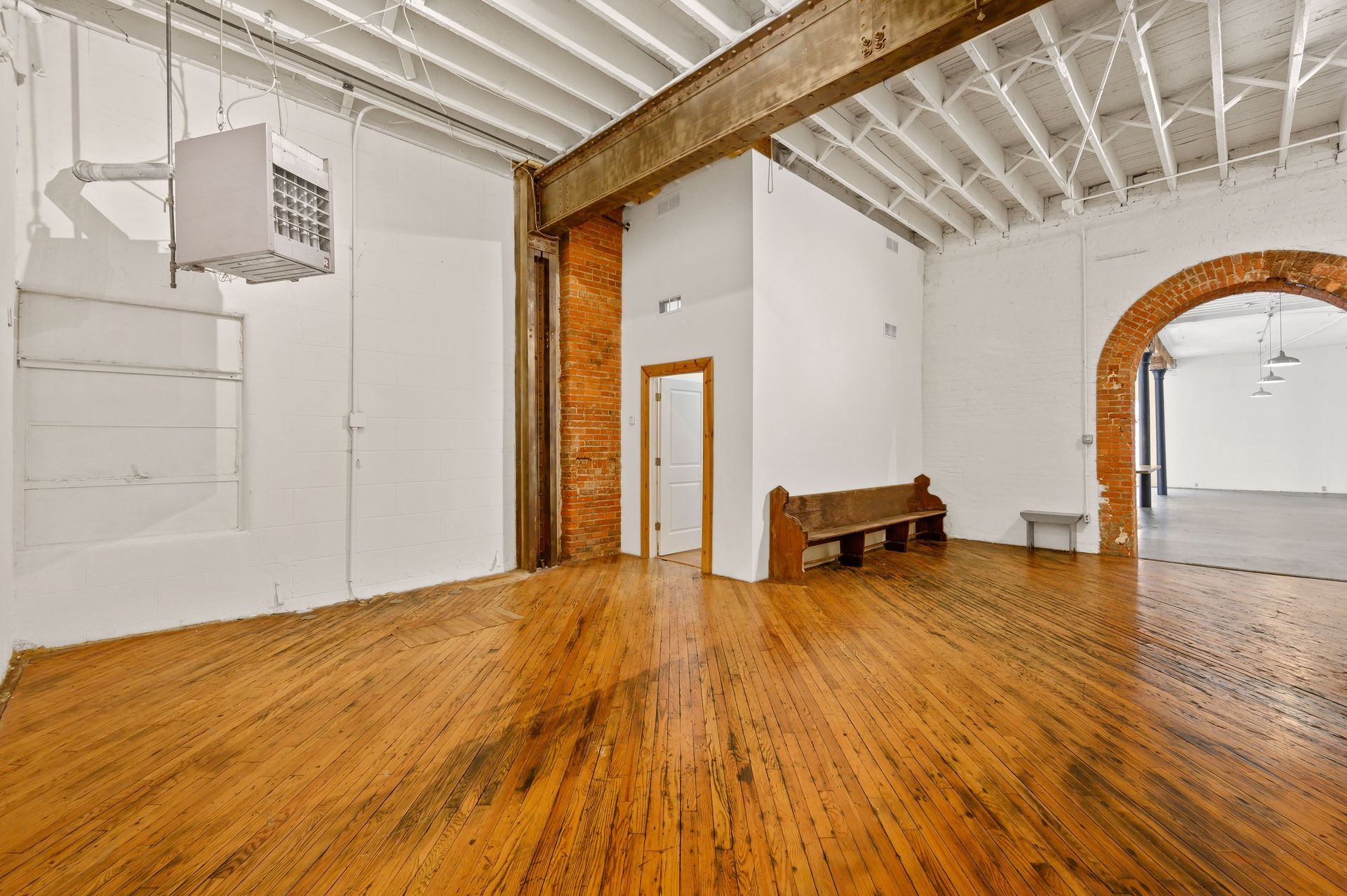 A large empty room with wooden floors and white walls.