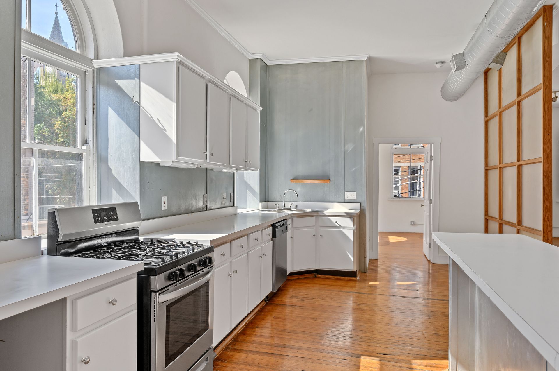 An empty kitchen with white cabinets and a stove