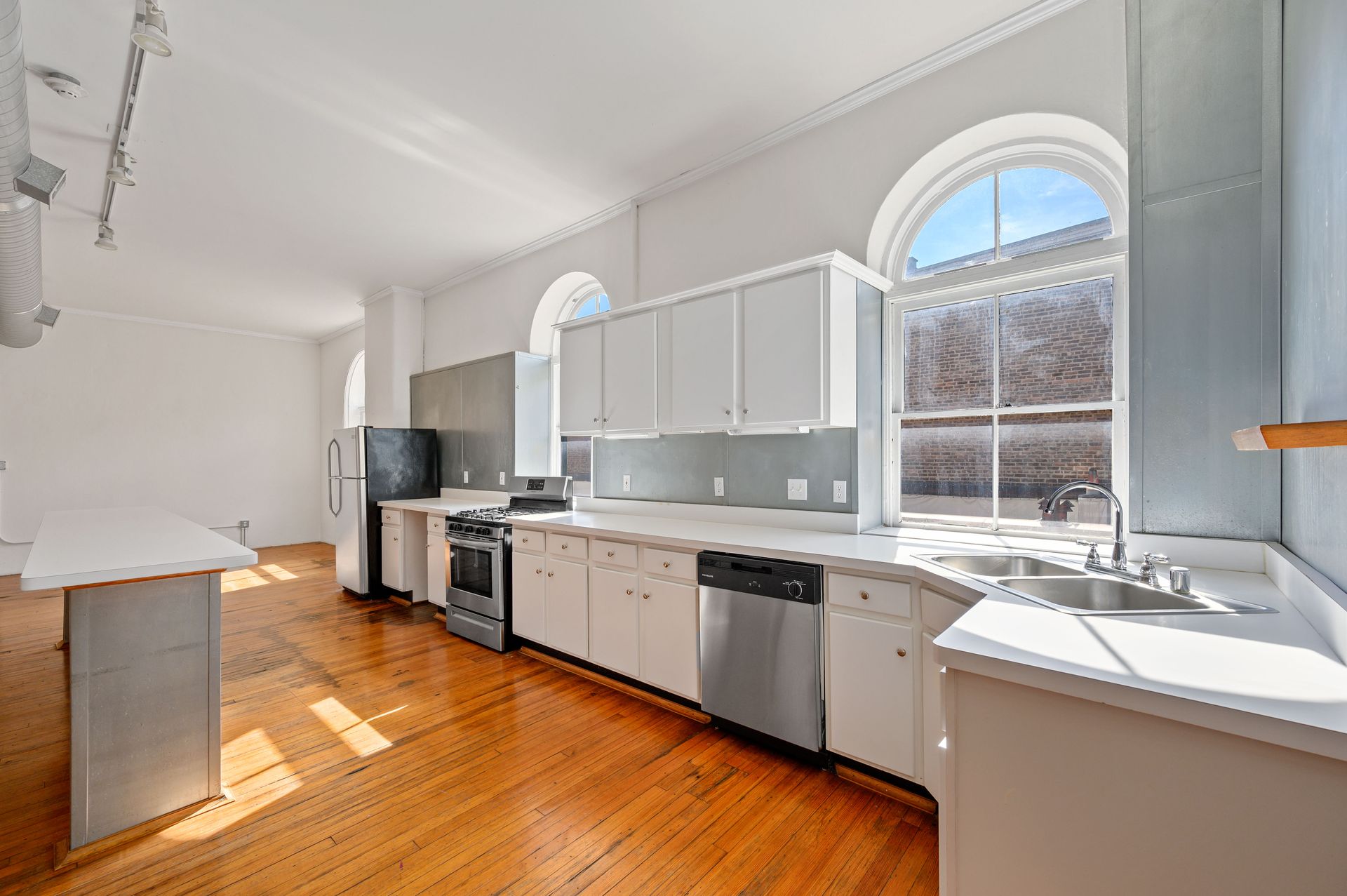 An empty kitchen with white cabinets and stainless steel appliances