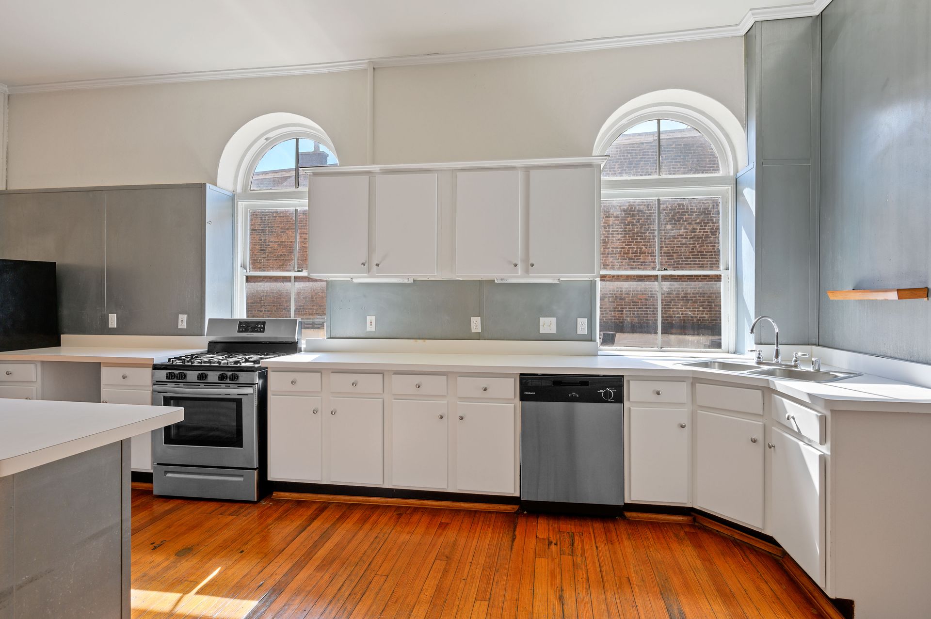 A kitchen with white cabinets and hardwood floors