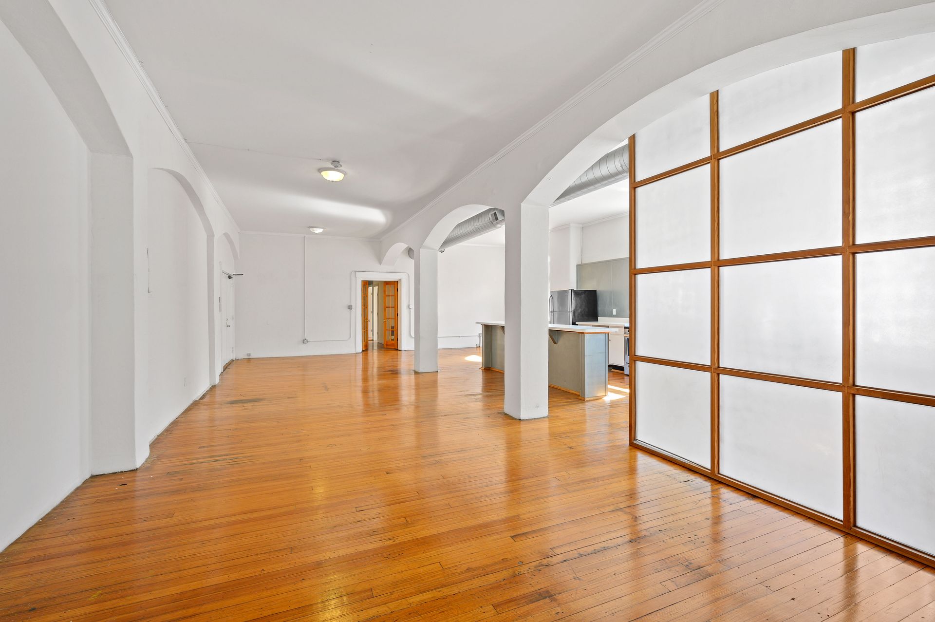 A large empty room with hardwood floors and white walls.