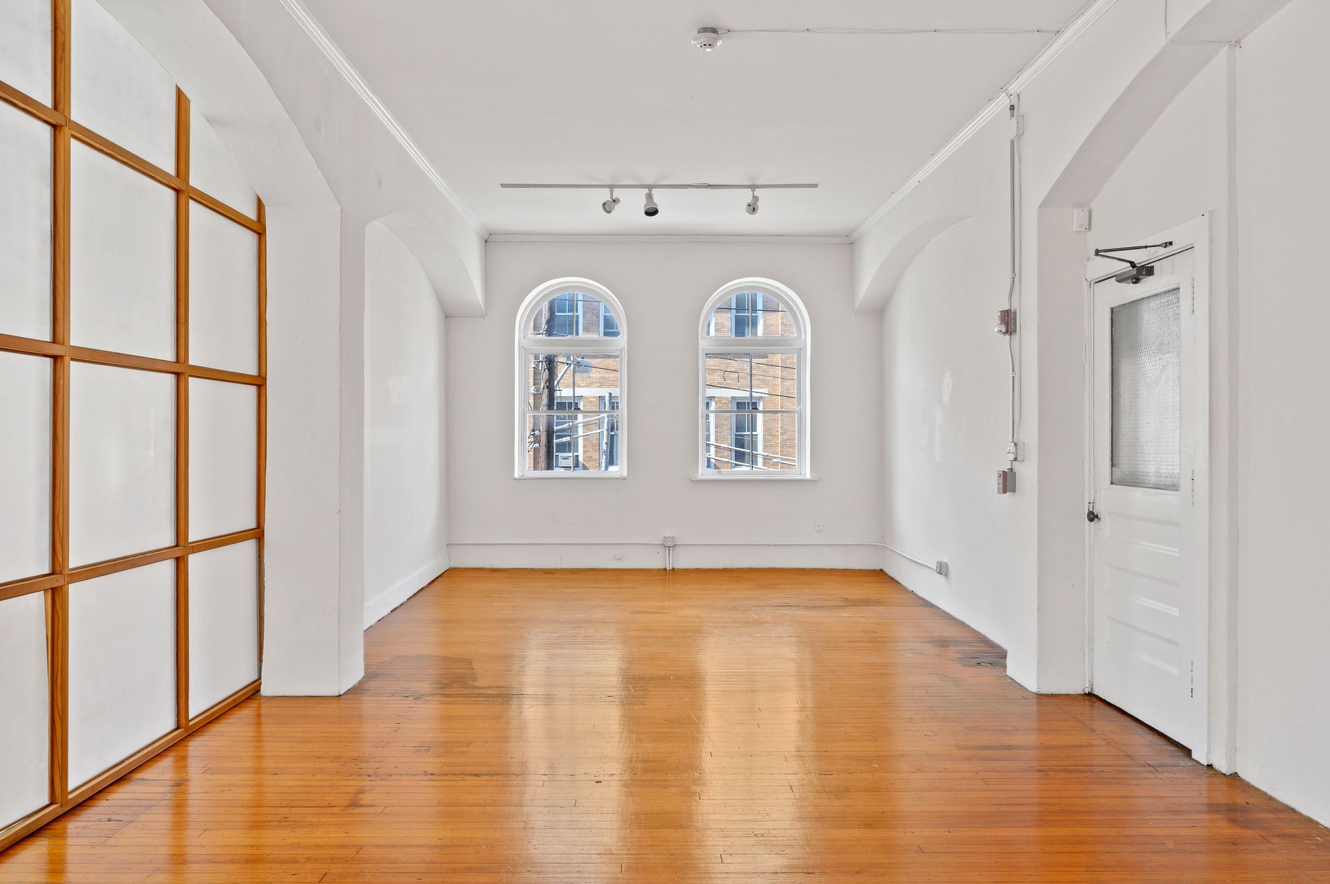 A large empty room with wooden floors and white walls.