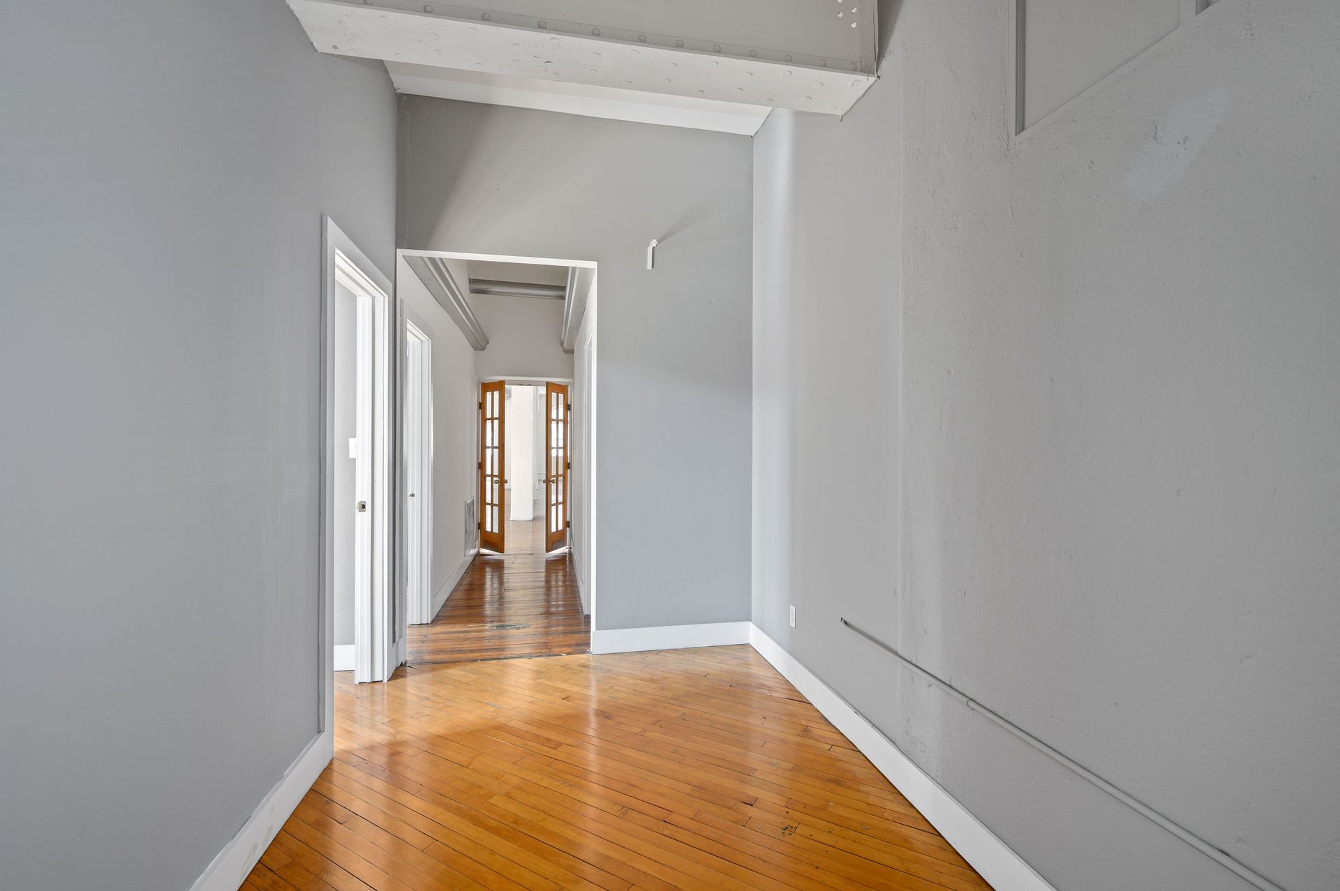 An empty hallway with wooden floors and gray walls