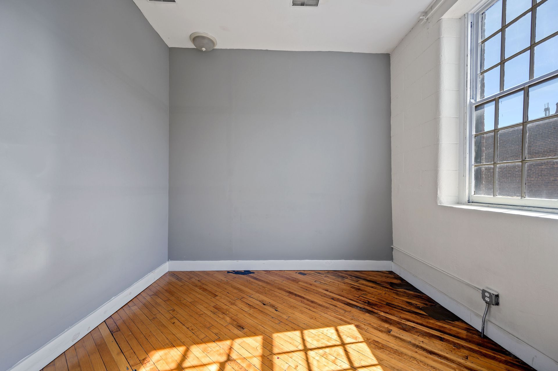 An empty room with a wooden floor and a window.
