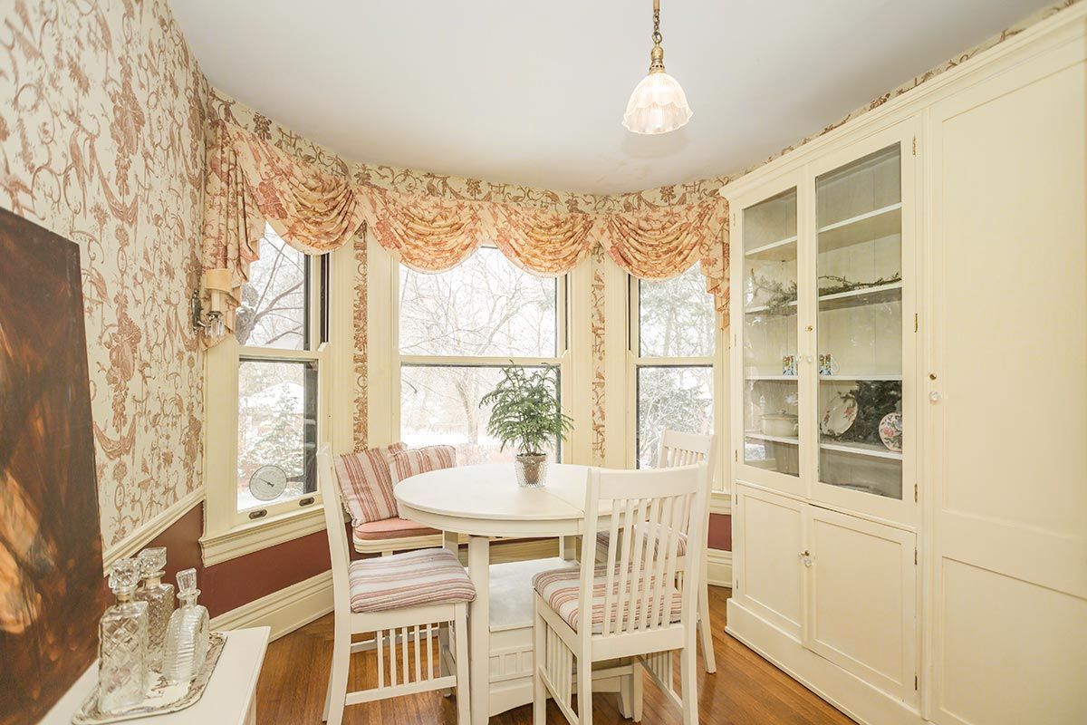 A dining room with a table and chairs and a painting on the wall.
