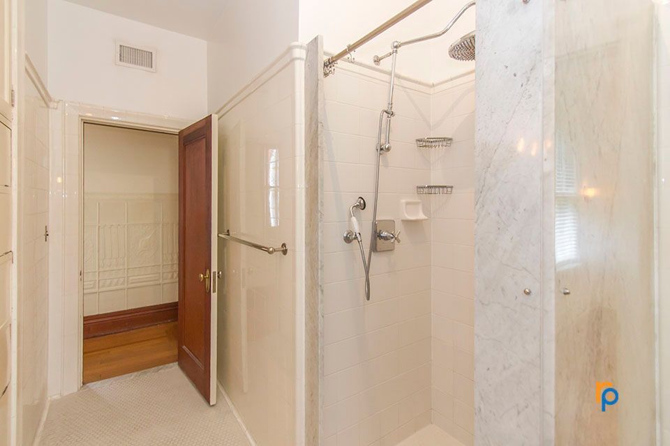 A bathroom with a walk in shower and a closet.