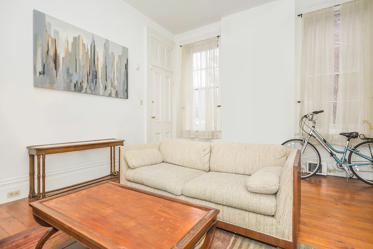 A living room with a couch , coffee table , and bicycle.
