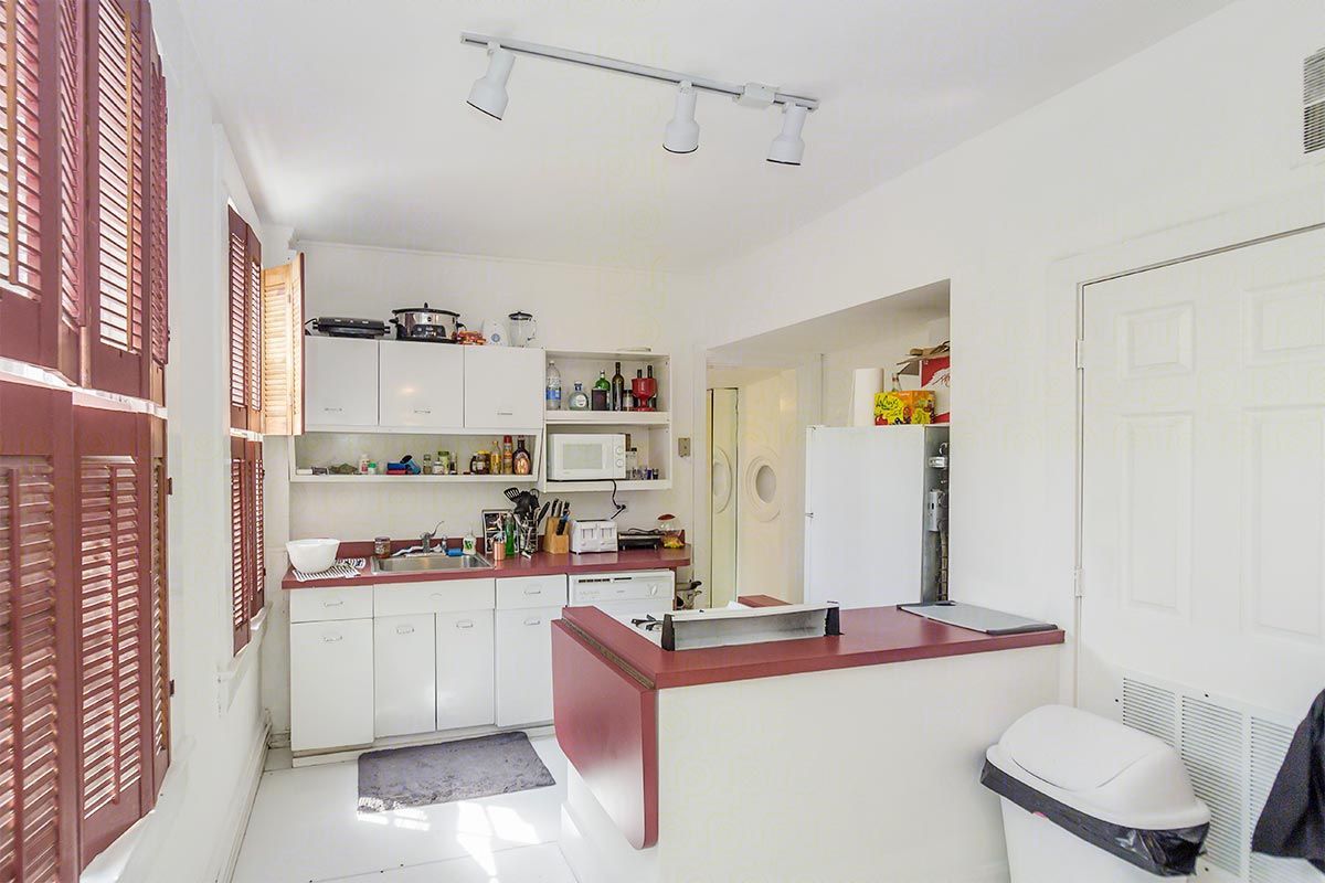 A kitchen with white cabinets and a red counter top.