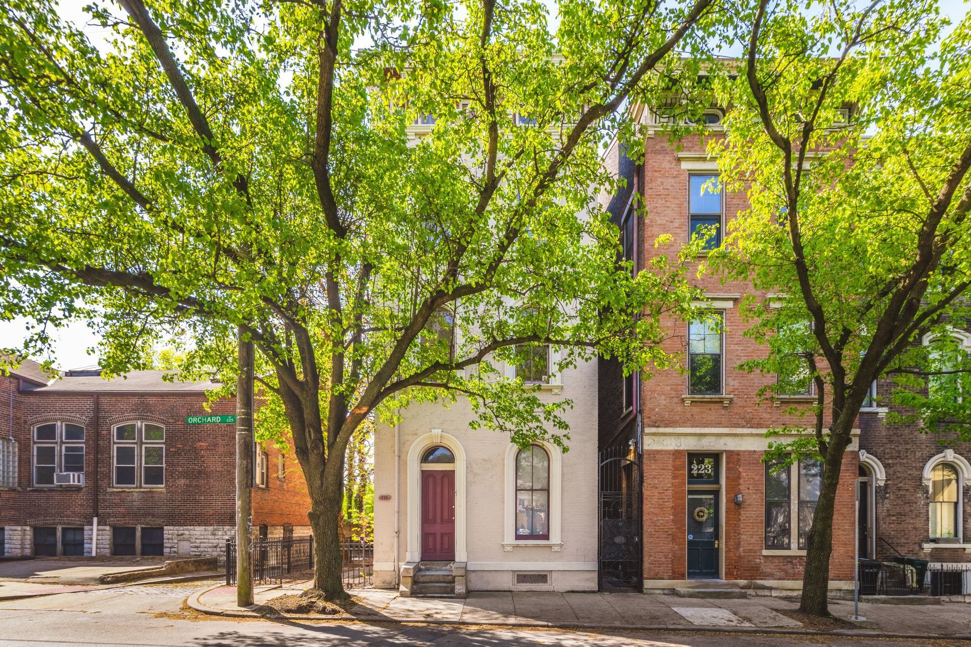 A row of brick buildings with trees in front of them on a sunny day.