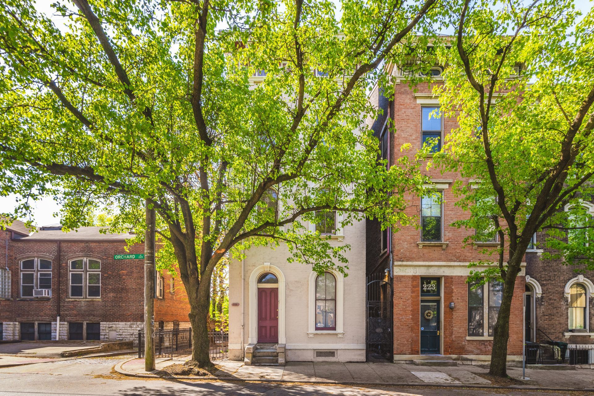 A row of brick buildings with trees in front of them on a sunny day.