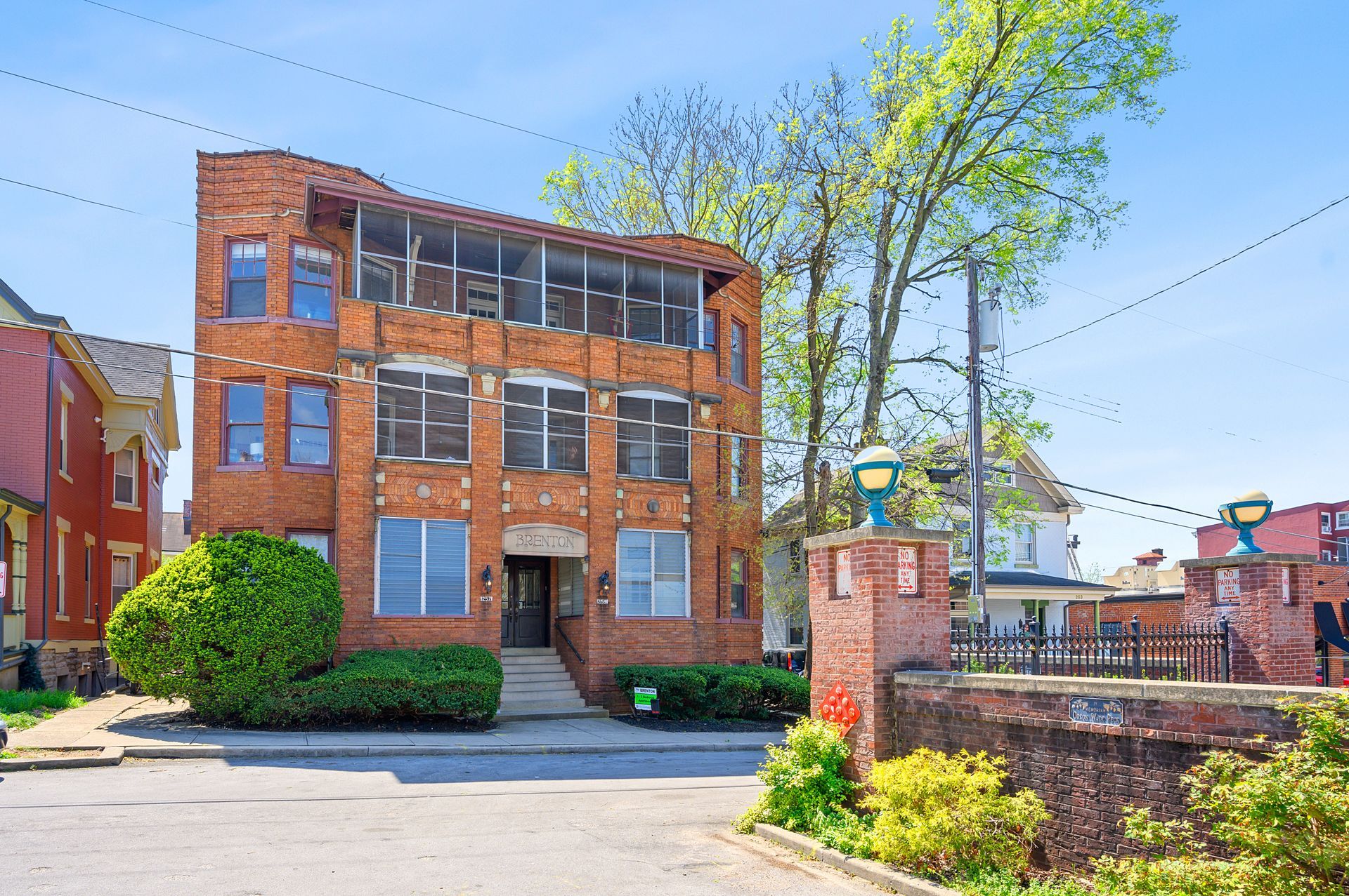 A large brick building with a lot of windows is surrounded by trees and bushes.