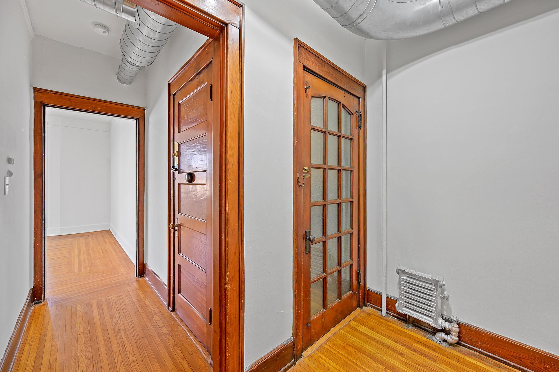 A hallway in a house with wooden floors and white walls.