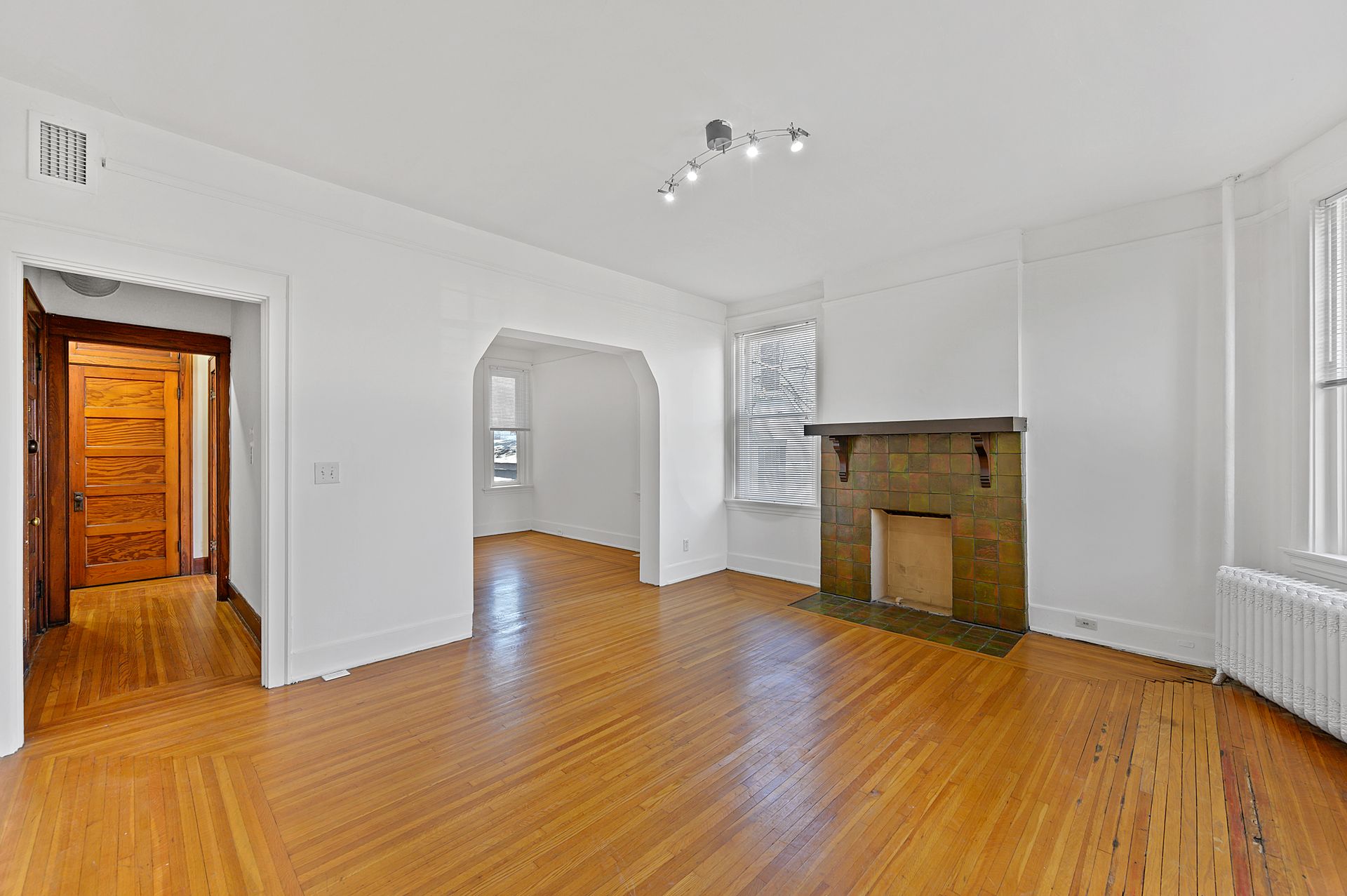 An empty living room with hardwood floors and a fireplace.