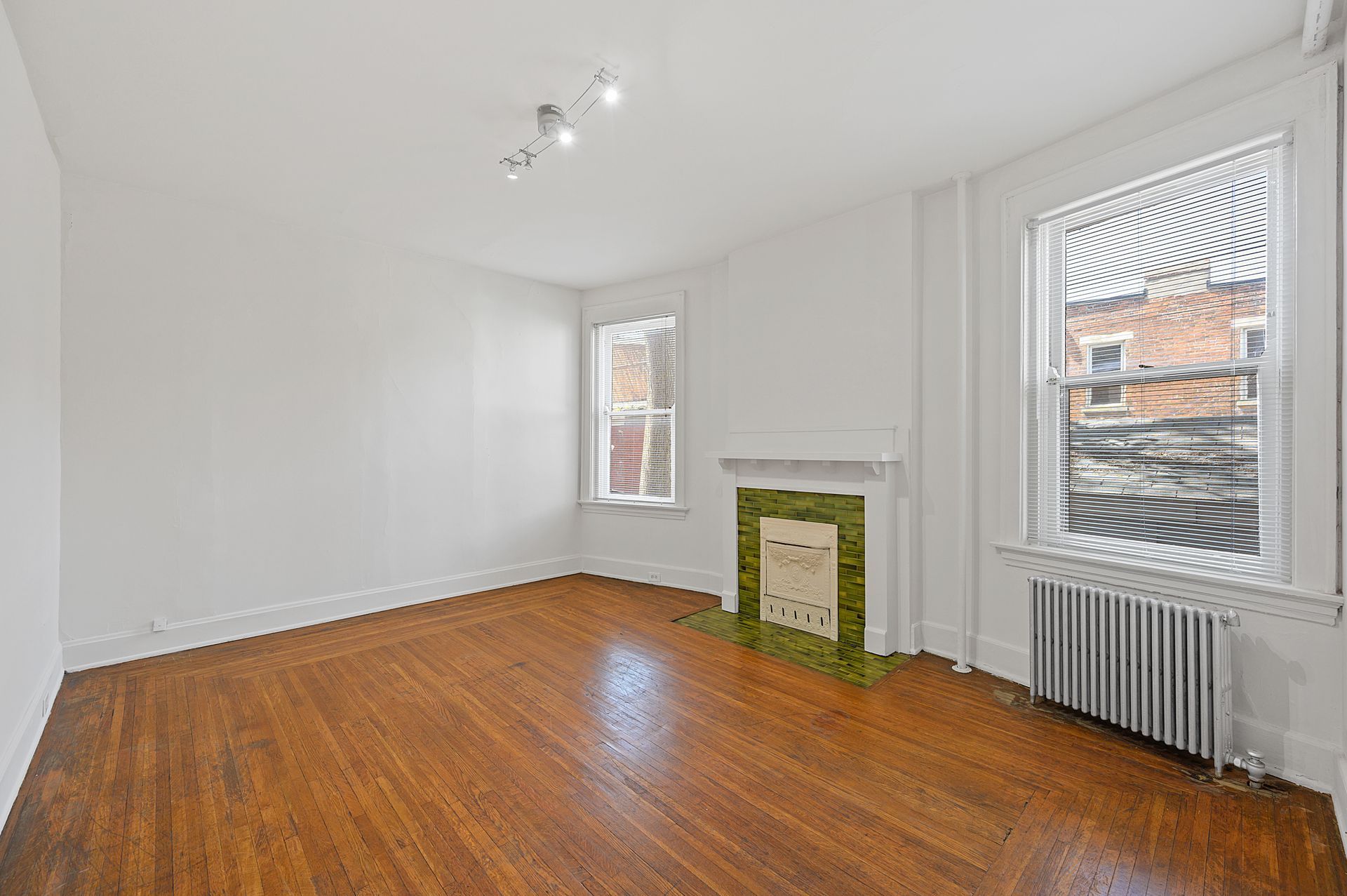 An empty living room with hardwood floors and a fireplace.