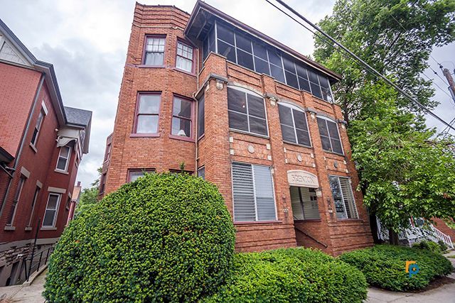 A large brick building with lots of windows and bushes in front of it.