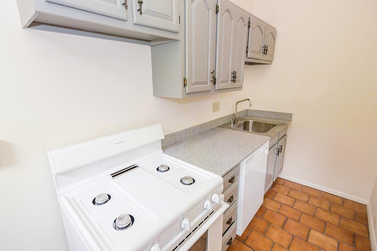 A kitchen with a stove , sink , and cabinets.