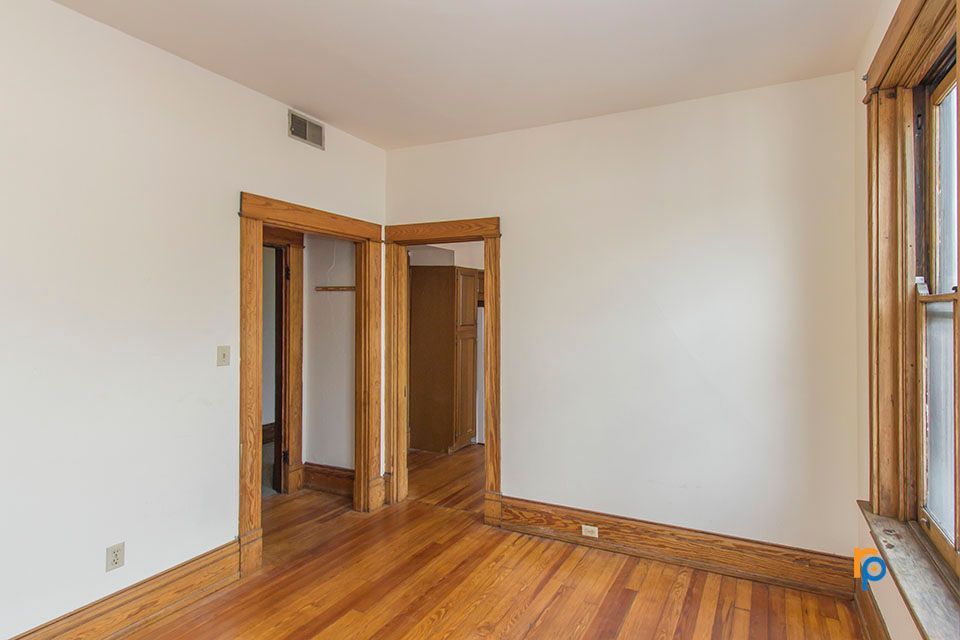 An empty room with hardwood floors and white walls.