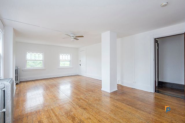 An empty living room with hardwood floors and a ceiling fan.