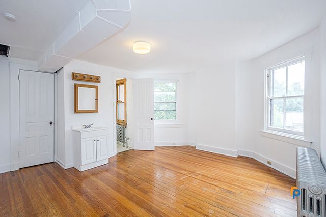 A large empty room with hardwood floors and white walls.