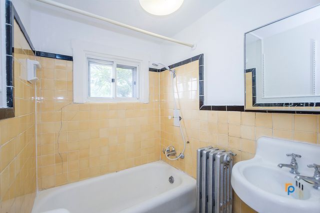 A bathroom with a tub , sink , mirror and window.